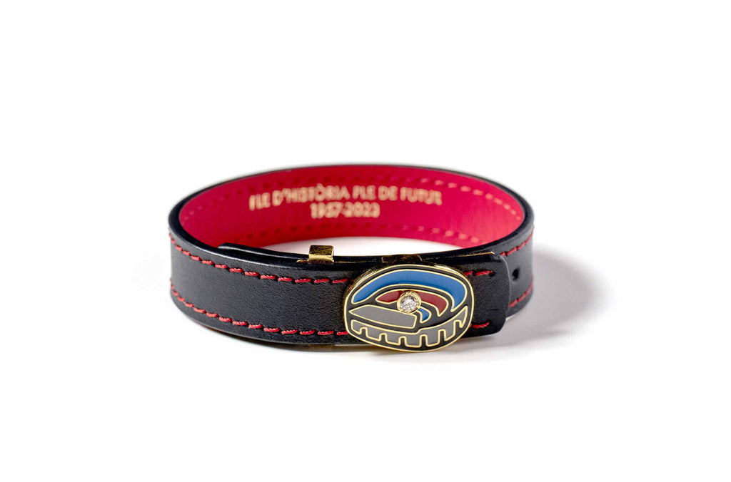 Pulsera 1957 sobre fondo blanco. La pulsera 1957, es una pulsera del FC Barcelona que cuenta con un diamante de 0.10 quilates engastado en su centro, acabada en oro de 18K y esmalte. Destaca por su color rojo y azul blaugrana.